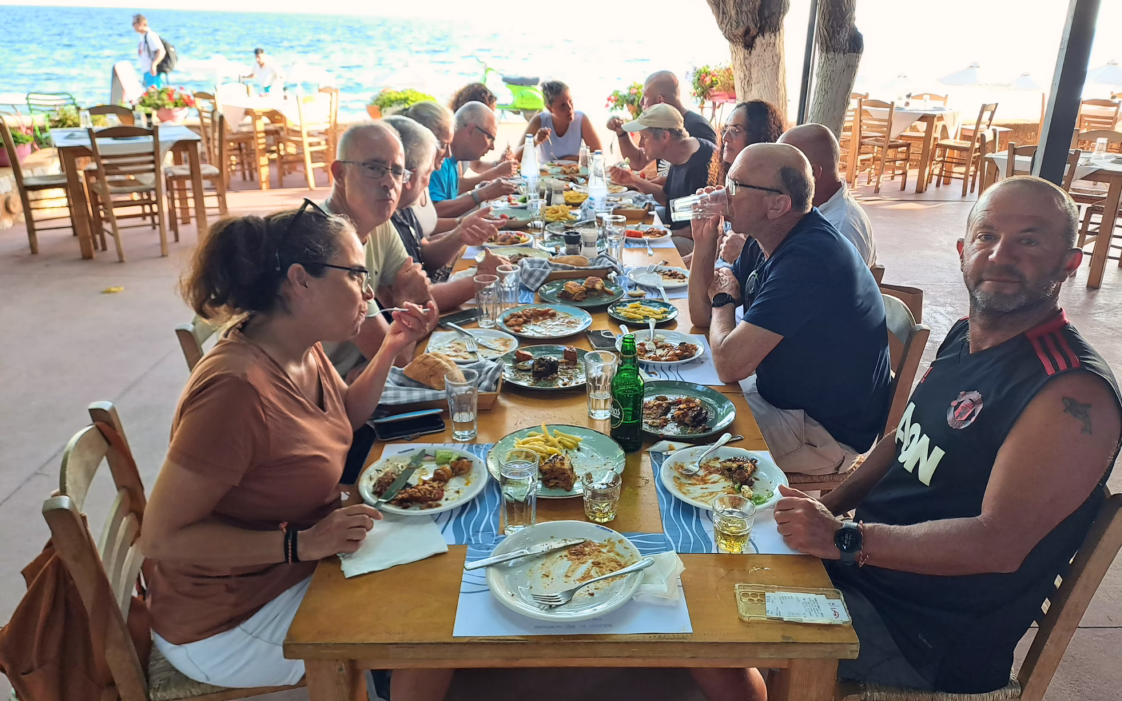 Group enjoying a shared meal at a seaside taverna in Nafplio, Greece