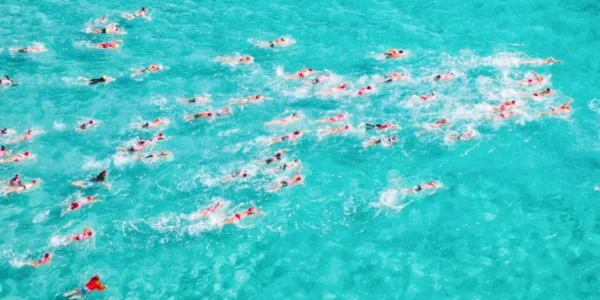 Open water swimmers moving together through turquoise sea in Nafplio, Greece