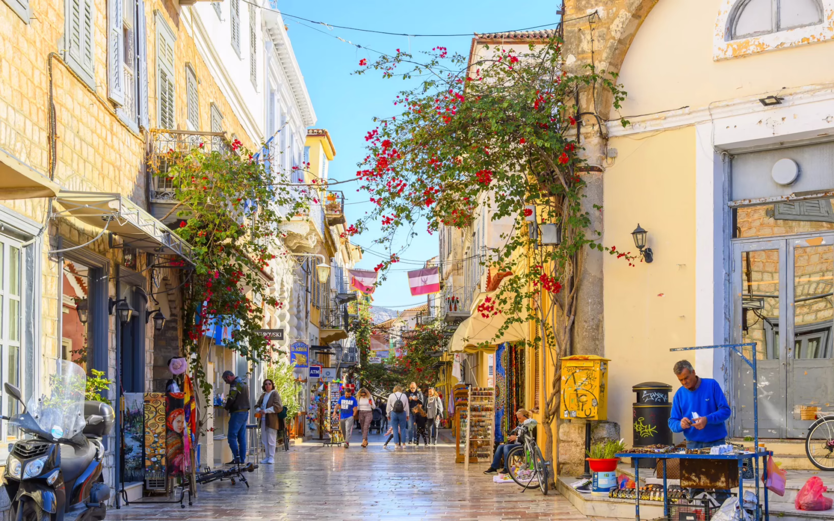 Pedestrian street in Nafplio old town with shops, cafés, and bougainvillea, Peloponnese